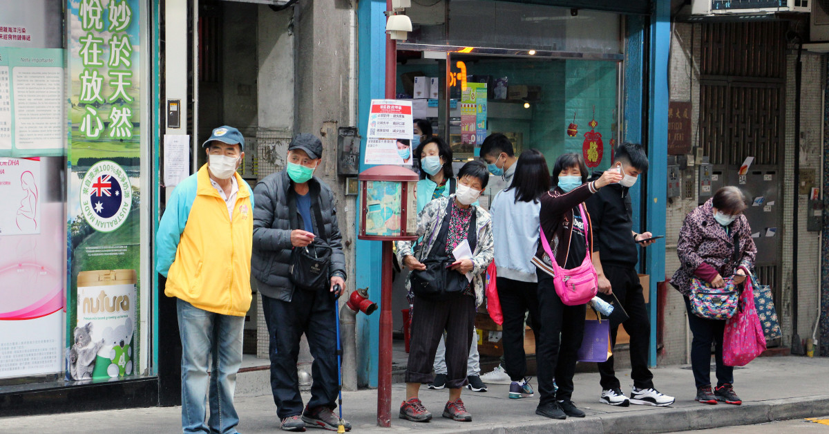 People waiting at a bus stop in Macau. Photo by Macau Photo Agency.